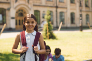 Beautiful little schoolgirl standing with rucksak